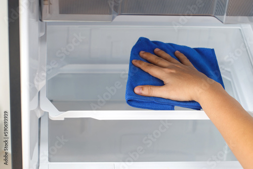 Employees use a cloth to clean the refrigerator.