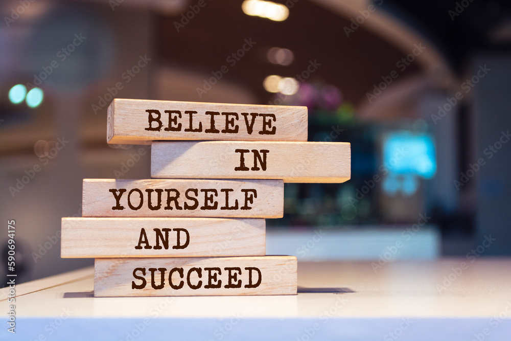 Wooden blocks with words 'Believe in yourself and succeed'.