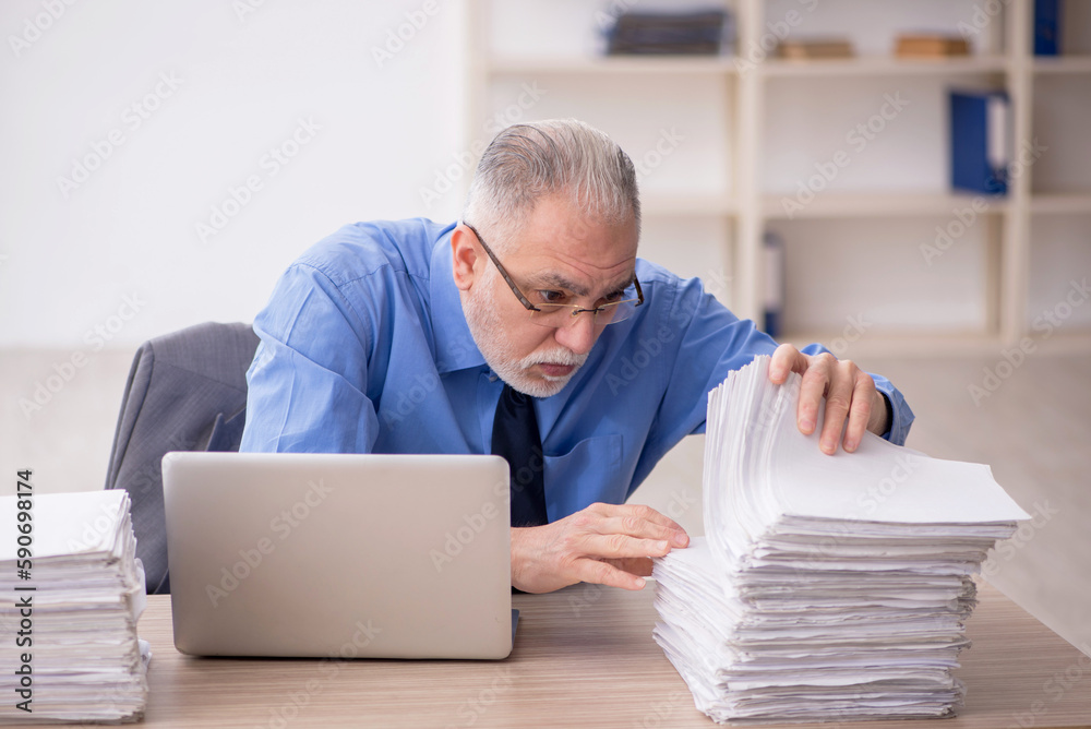 Obraz premium Old male employee and too much work in the office