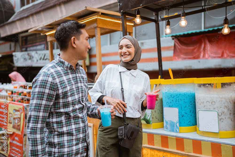 portrait of happy young muslim couple buy drink from a street vendor portrait of happy young muslim couple buy drink from a street vendor