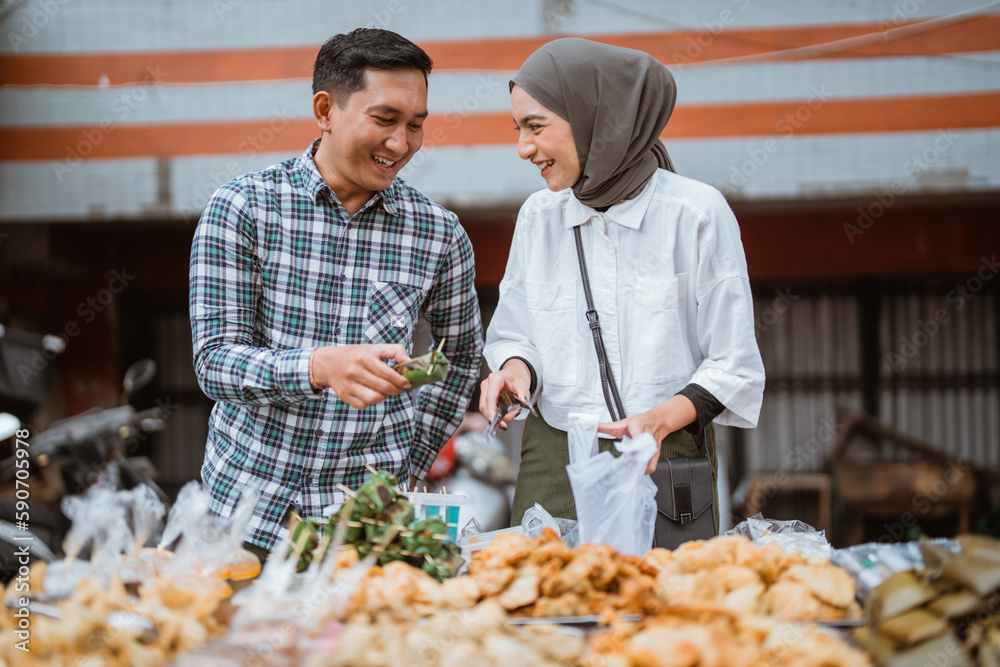 beautiful muslim couple are shopping in a food stall or street vendor during ramadan