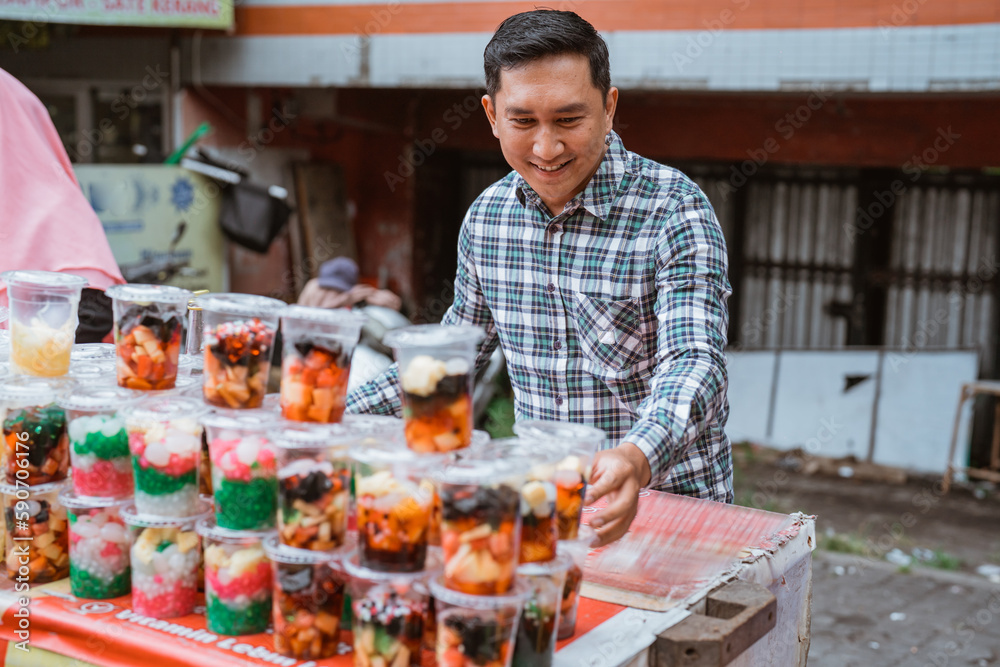 young man sell mix fruit drink and jelly juice. street food vendor sell some traditional fruit beverage on plastic cup with colorful color
