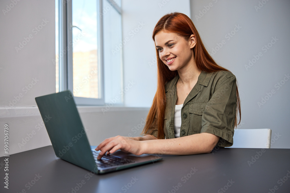 portrait of a happy, joyful woman sitting at a laptop and working in the office