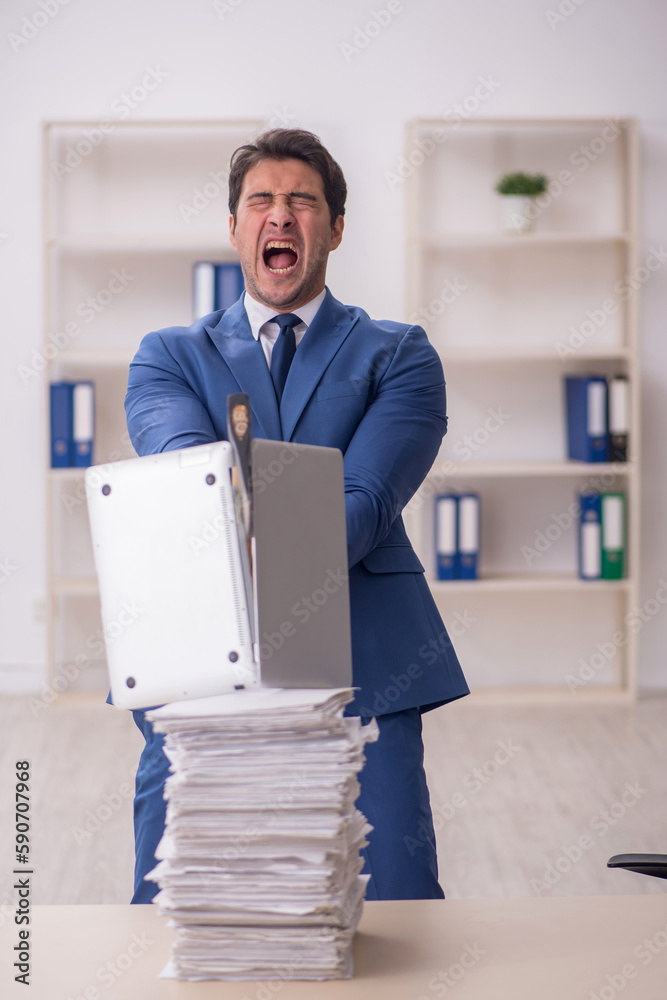 Young male employee unhappy with excessive work in the office Young male employee unhappy with excessive work in the office
