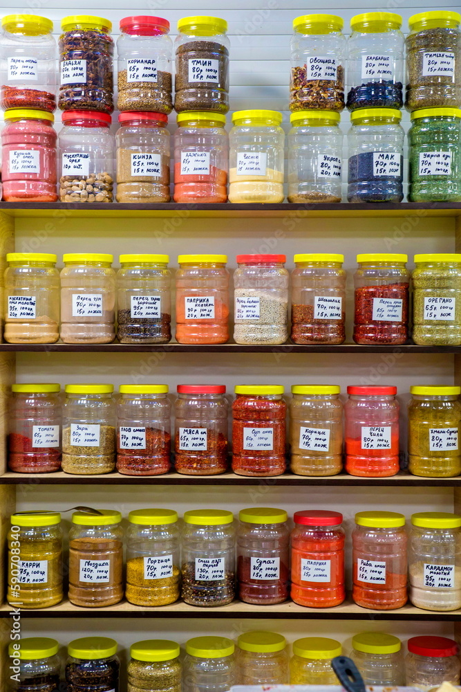 a large selection of different spices on the store shelf. Text in Russian: cumin, coriander, cinnamon, pepper, Zira, mustard, cloves, paprika, garlic. a large selection of different spices on the store shelf. Text in Russian: cumin, coriander, cinnamon, pepper, Zira, mustard, cloves, paprika, garlic.