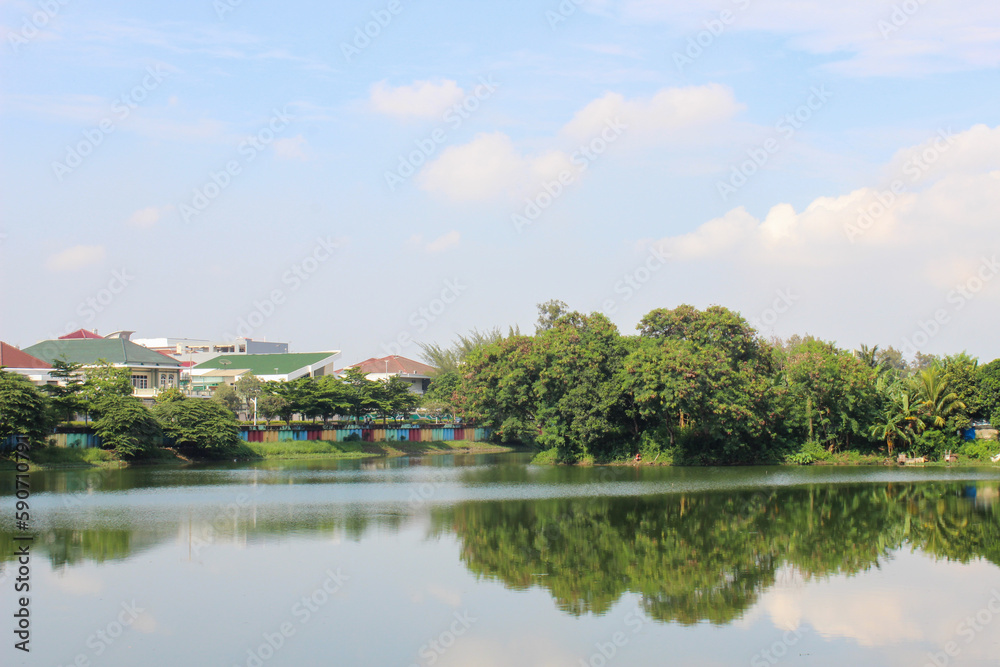 small island in the middle of sunter lake or danau sunter with bright sky, a small island with trees in the middle of a lake in Jakarta