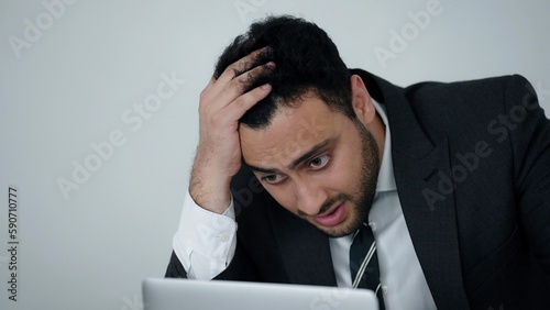 Obraz na plátně Indian businessman in a suit using labtop and being worried and irritated after