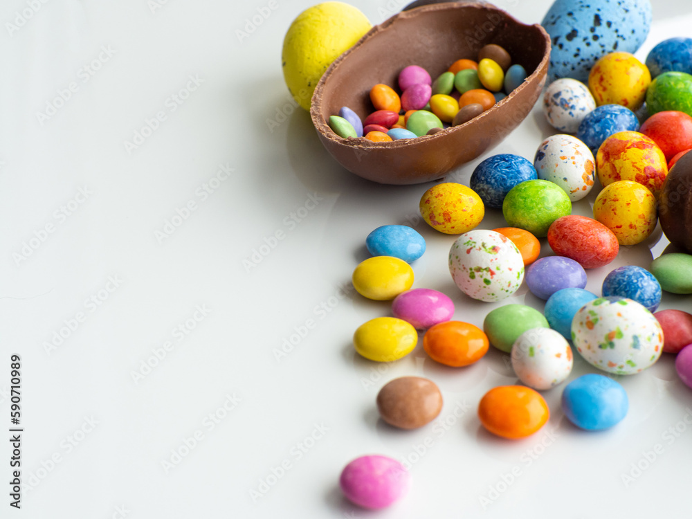 Sweet Easter concept. Colorful and chocolate easter eggs with sweet dragee on white background with copy space. Design for a greeting card for the Easter holiday. Flat lay. Preparation for holiday. Sweet Easter concept. Colorful and chocolate easter eggs with sweet dragee on white background with copy space. Design for a greeting card for the Easter holiday. Flat lay. Preparation for holiday.