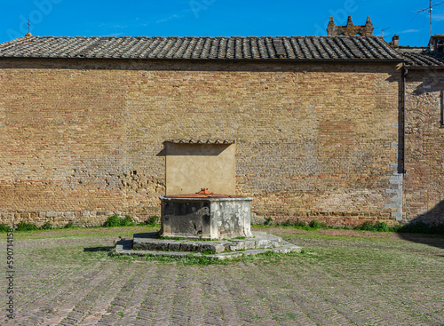 the central cistern of  St.Augustine square and the St.Augustine church, a most important church in San Gimignano, Siena province,Tuscany region,Italy photo