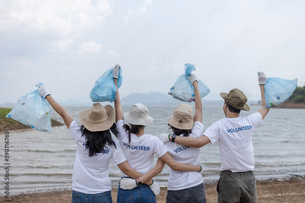 Group of volunteers cheerful success arms raised holding rubbish bags ...