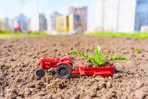 Fotografie Toy Tractor with Young Green Shoots on Freshly Plowed Land