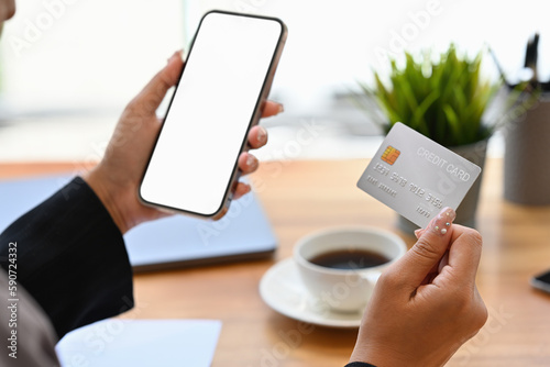 Close up view of female consumer holding credit card and smartphone. E-commerce, online banking transaction and shopping online. © saltdium
