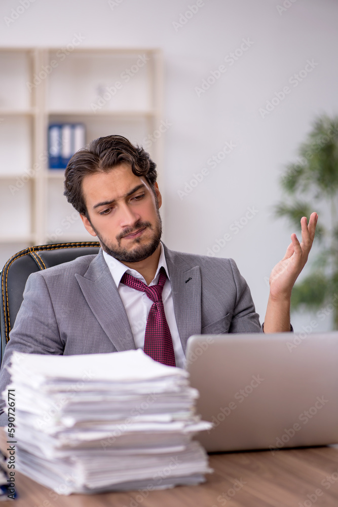 Naklejka premium Young male employee and too much work in the office