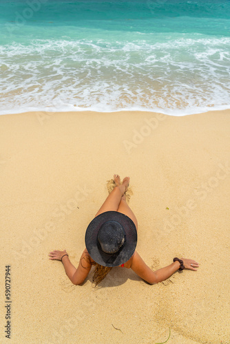 Woman with reb swimsuit and black hat at the beach in Bali indonesia