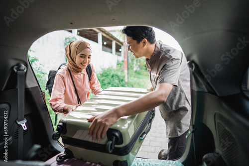 muslim couple packing suitcase in the car trunk for eid mubarak holiday