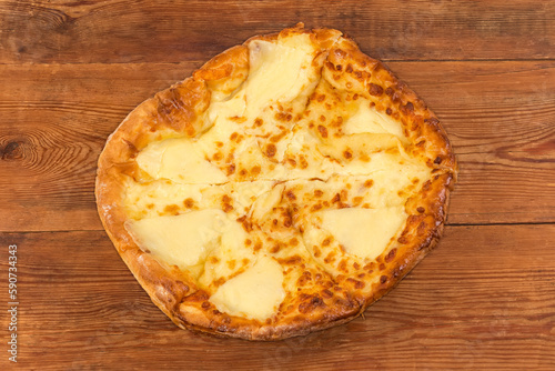 Baked round khachapuri on dish on rustic table, top view photo