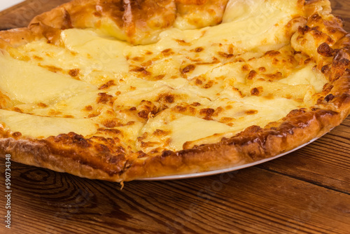 Baked khachapuri on dish on rustic table, close-up photo