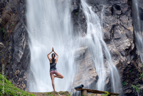 Fototapeta Naklejka Na Ścianę i Meble -  Asian traveller woman pose yoga in lotus pose with waterfall background