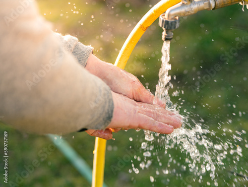 Washing hands after ground works in garden from garden tap