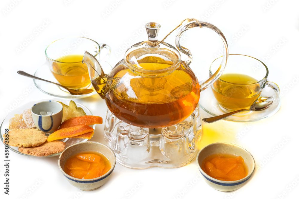 Glass tea pot with plum mango tea and ham,cups and crystalized fruits on white background Glass tea pot with plum mango tea and ham,cups and crystalized fruits on white background