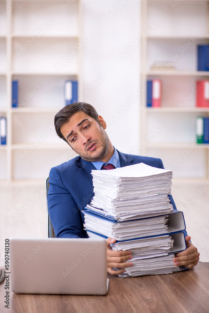 Young male employee and too much work in the office Young male employee and too much work in the office