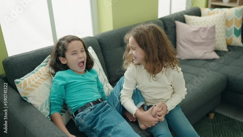 Adorable girls sitting on sofa laughing for feet tickles at home