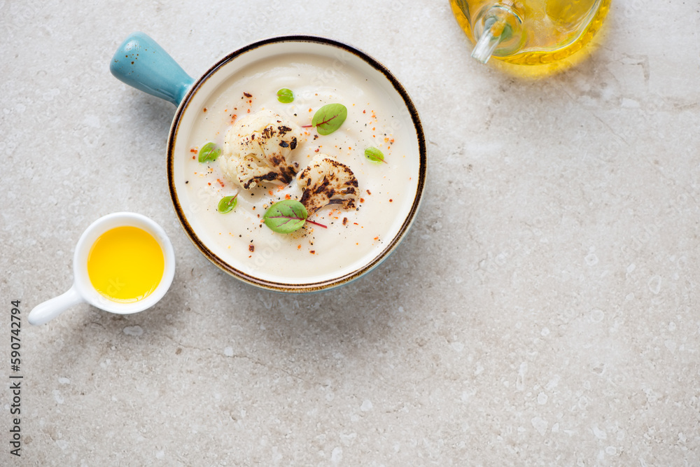 Turquoise serving bowl with cauliflower cream-soup, top view on a beige stone background, horizontal shot with copy space Turquoise serving bowl with cauliflower cream-soup, top view on a beige stone background, horizontal shot with copy space
