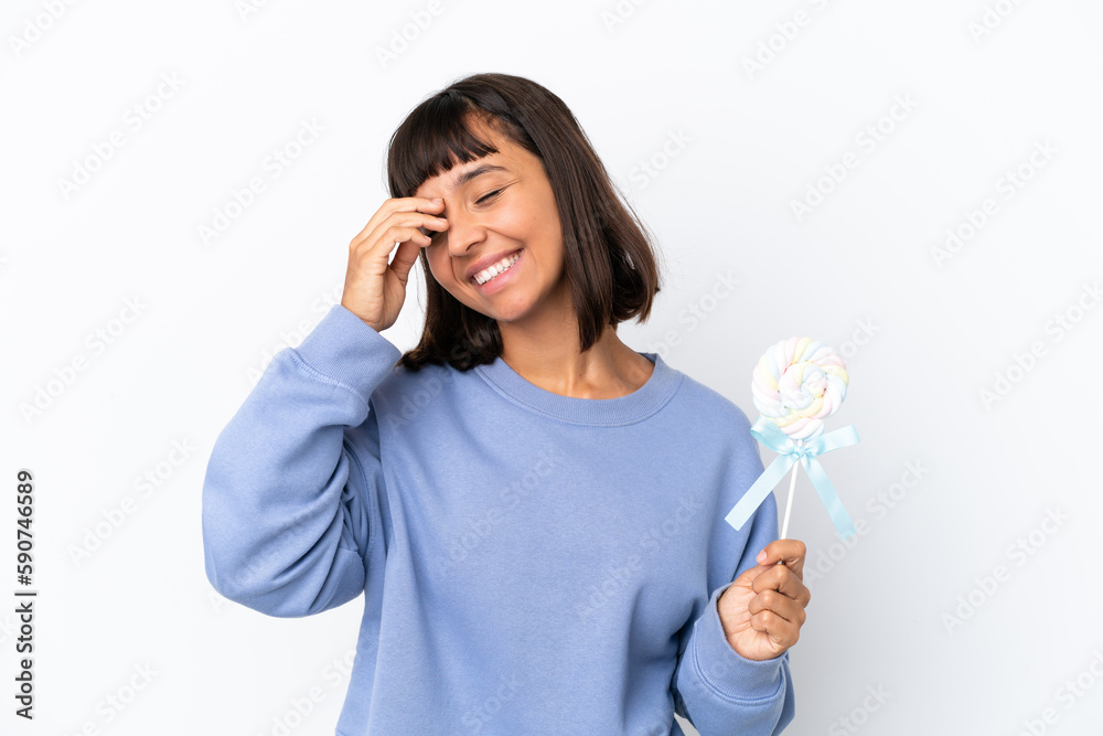 Young mixed race woman holding a lollipop isolated on white background smiling a lot Young mixed race woman holding a lollipop isolated on white background smiling a lot