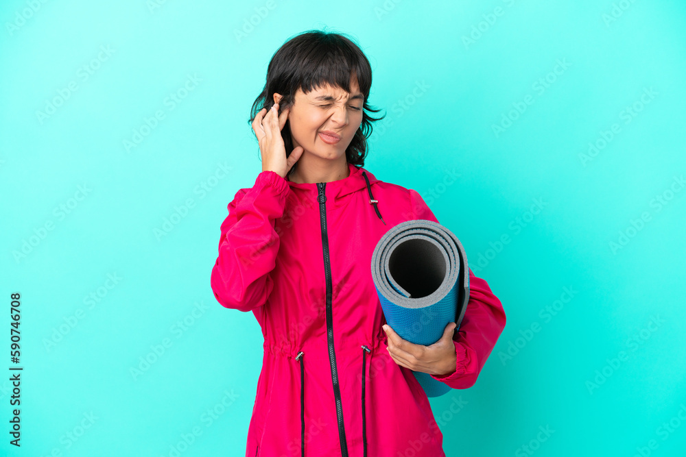 Obraz premium Young girl going to yoga classes while holding a mat isolated on blue background frustrated and covering ears