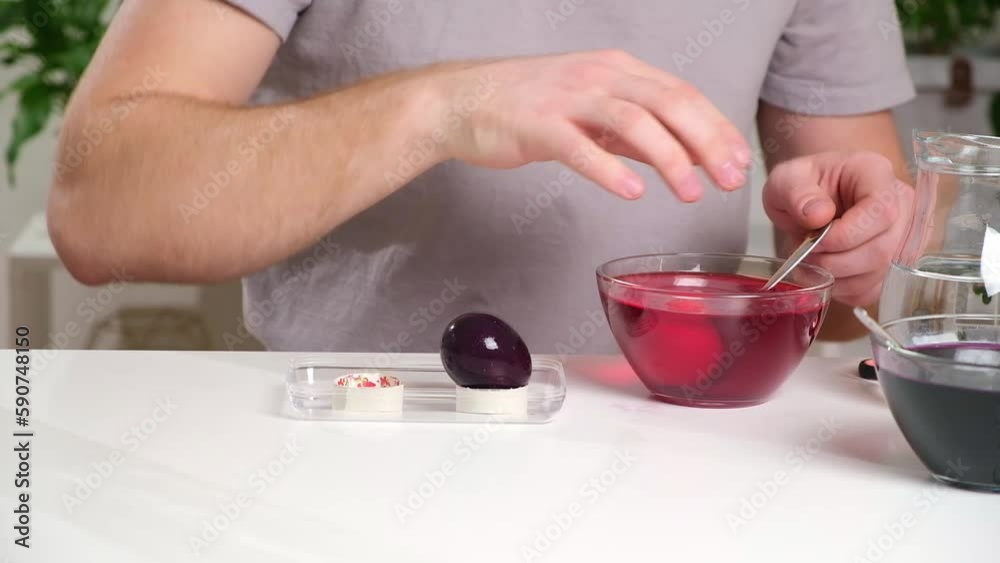 A man takes out colored Easter eggs from colored water. Dyeing easter eggs with food coloring is the first step in favorite Easter egg decorating ideas. A man takes out colored Easter eggs from colored water. Dyeing easter eggs with food coloring is the first step in favorite Easter egg decorating ideas.