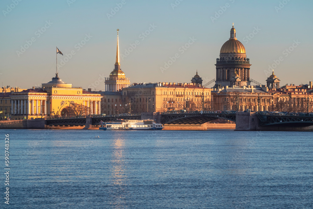 Tourist ship is sailing under the bridge. Spring St. Petersburg with a view of St. Isaac's Cathedral. View from the Neva River. Sunset view of the Palace Bridge, city life, postcard views.