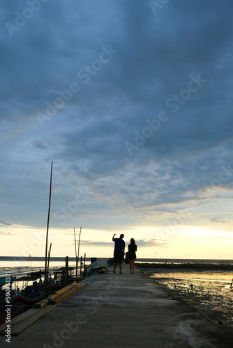 Beautiful sunset at Kampung kuala Kuar Jawa fishing village, Alor setar, Kedah. Silhouette of a couple standing at the pier.