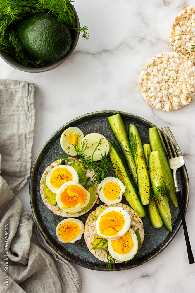 Healthy breakfasts, rice cakes with avocado and boiled eggs with dill and cucumber with spices, healthy wholesome food, top view