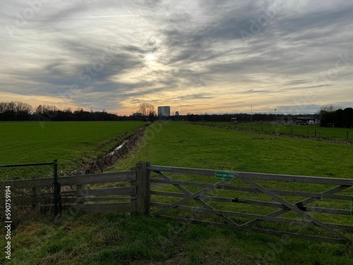 Fields with wooden fence and dramatic sunset cloudy sky on the horizon