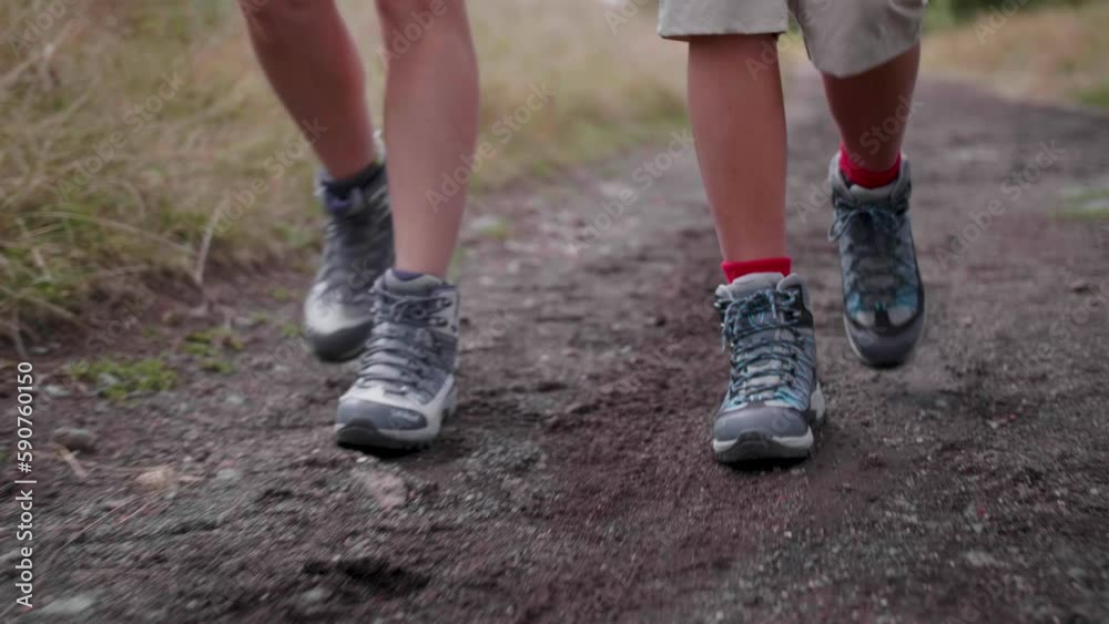 Closeup slow motion of two people walking on a rocky ground with hiking shoes Closeup slow motion of two people walking on a rocky ground with hiking shoes