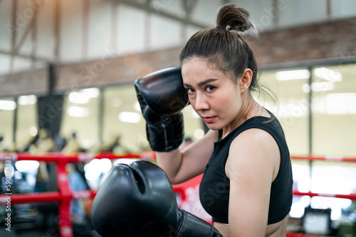 boxing confident woman punching wearing gloves. confident boxer coach training exercise to build muscle for body. determined tough female athlete trainer with gloves doing arms punching on gym ring