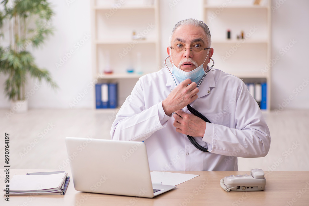Old male doctor working in the clinic during pandemic Old male doctor working in the clinic during pandemic