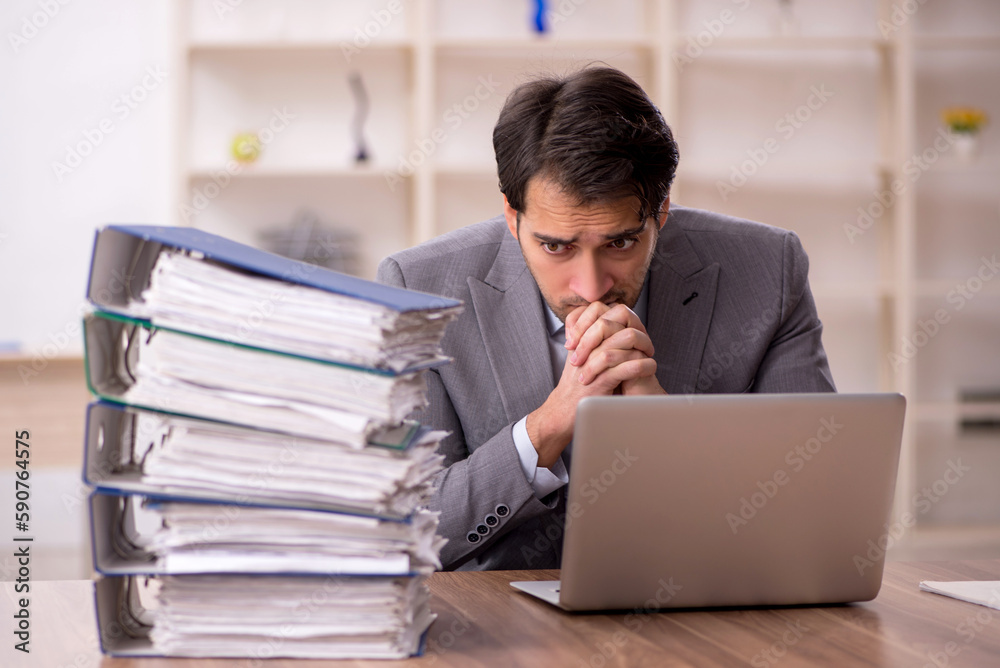 Young male employee and too much work in the office Young male employee and too much work in the office