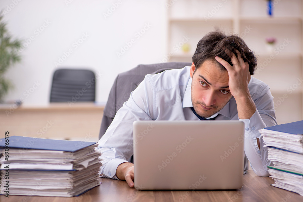 Young male employee and too much work in the office Young male employee and too much work in the office