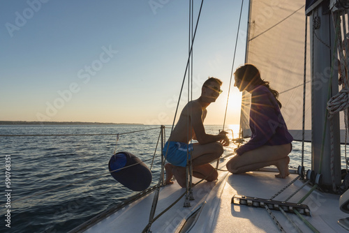 Couple kissing on a sailboat yacht sailing in the sea at colorful sunset