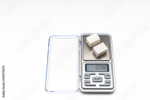 a sugar cube lies on a small scale.