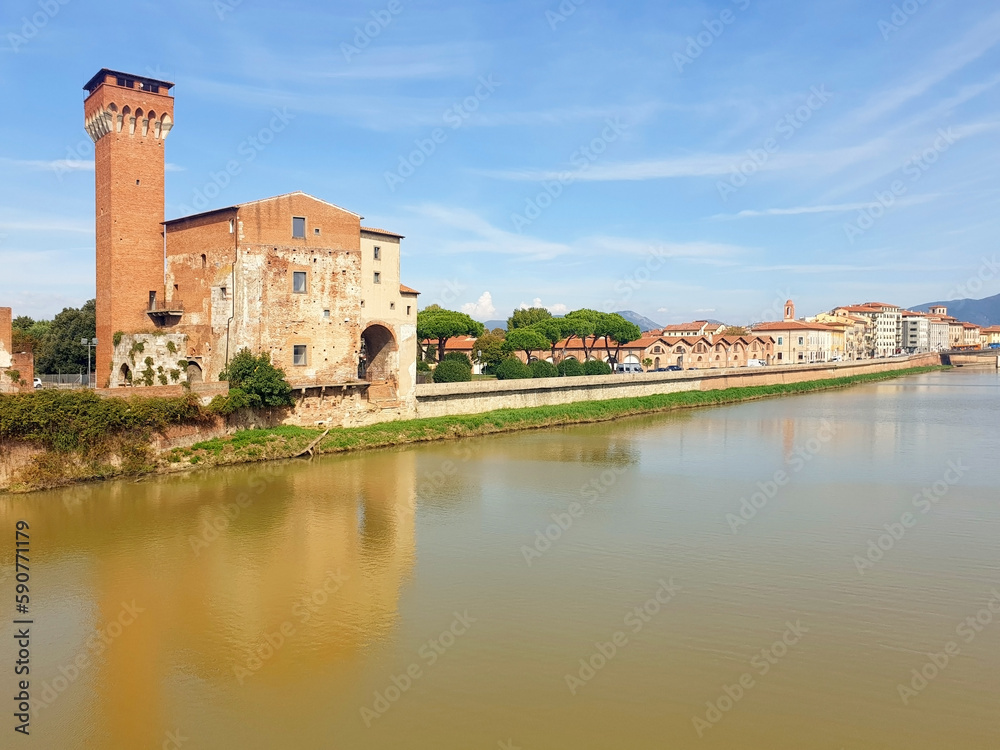 View of the brown tower Guelph and the street of Pisa from the bridge of the Arno river.