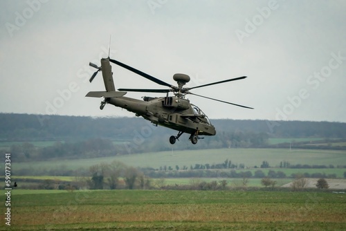 Military helicopter landing in a field