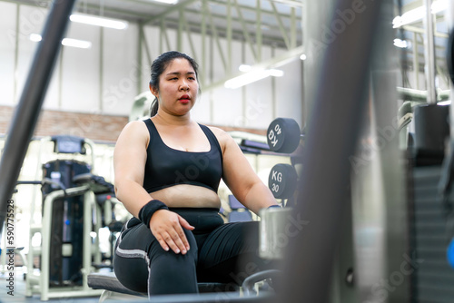 chubby motivated woman pulling workout machine. female gym member holding in heavy weight fighting to build strong muscle. determined person aim for changing life practice pulling up workout station