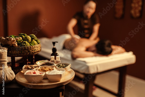 Healthy spa set on a table with customer relaxation massage on background.