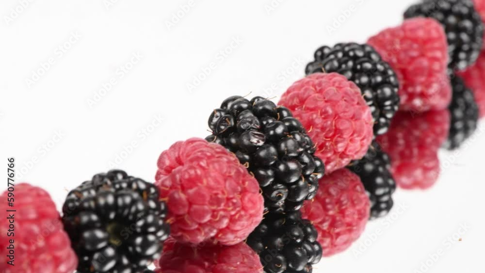 Blackberry and raspberry with reflection on white background. Move from bottom left to top right. Side view. Loop motion. Rotation 360. 4K UHD video footage 3840X2160.