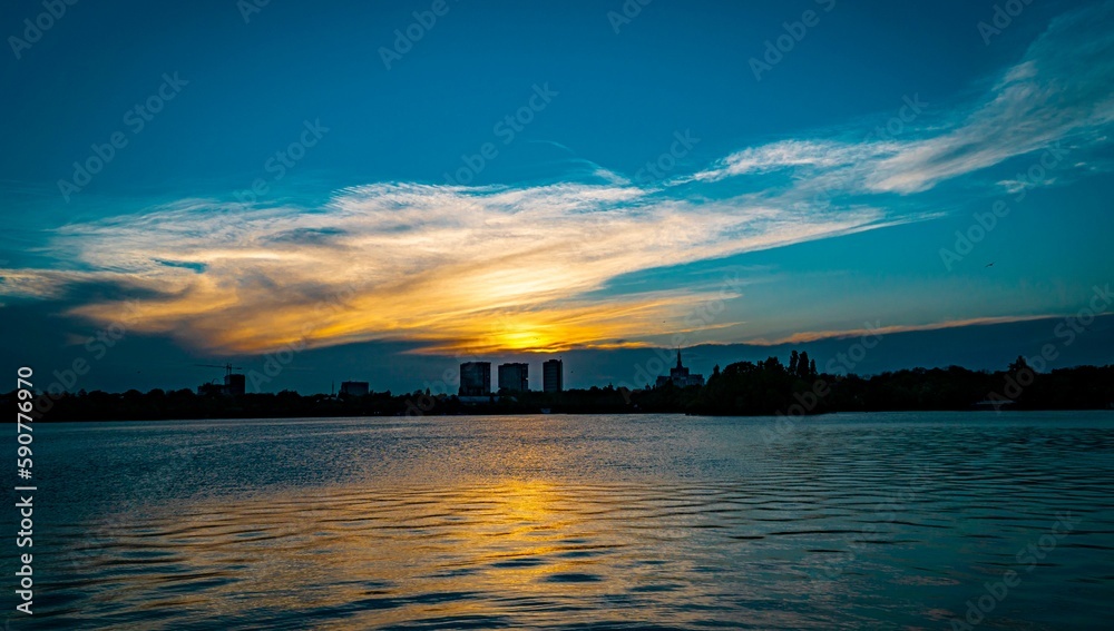Naklejka premium Blue sunset scene sky reflecting on the sea with silhouette city buildings on the horizon