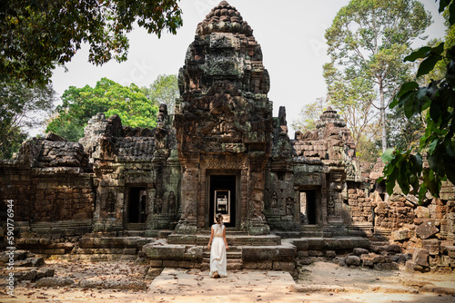 Young woman wearing white robe dress in ancient Khmer ruins, Angkor Wat