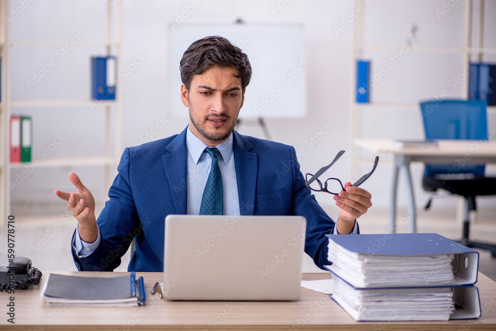 Young businessman employee and too much work in the office