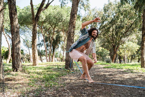 Happy man slacklining in the city park during summer day
